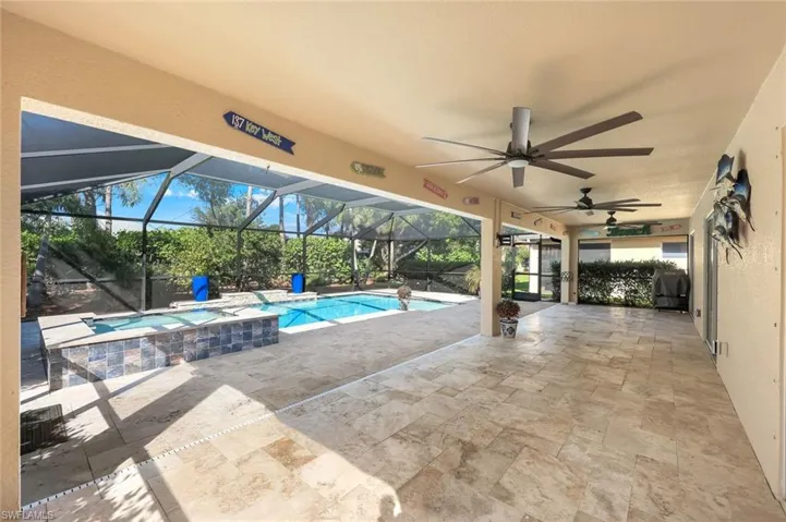 Huge covered outdoor area for entertaining, with a ceiling fan, a pool with connected hot tub, and screen enclosure