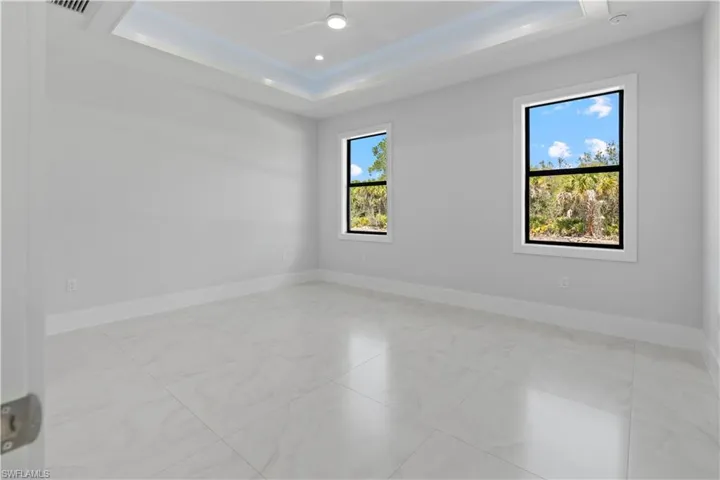 Empty room with a ceiling fan, recessed lighting, and a tray ceiling