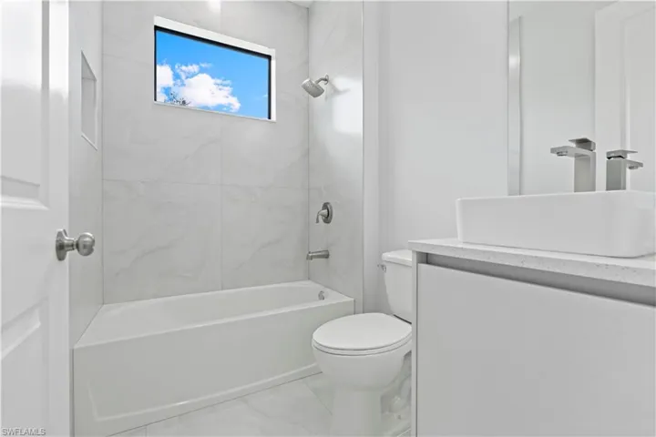 Full bath featuring vanity, bathing tub / shower combination, and light marble finish floors