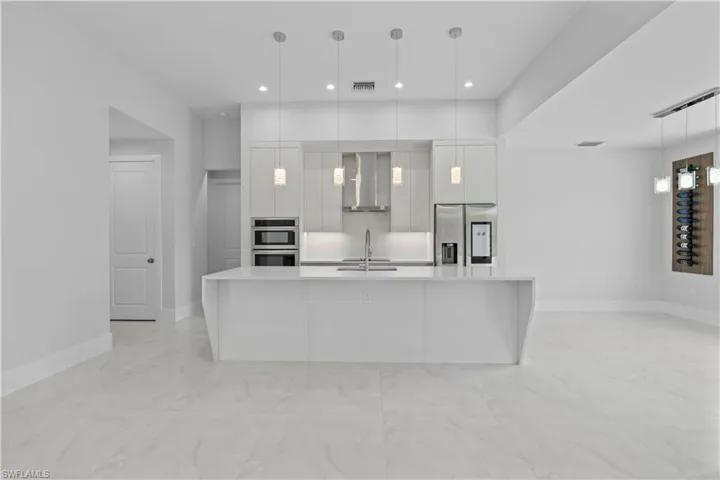 Kitchen with modern cabinets, a spacious island, pendant lighting, and light stone countertops