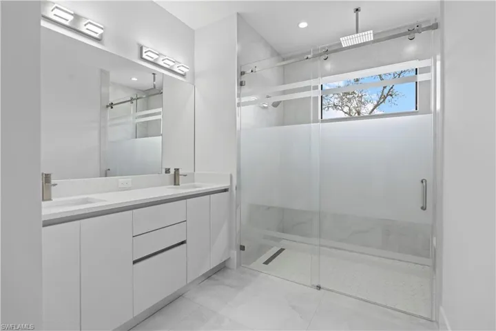 Bathroom featuring double vanity and a marble finish shower