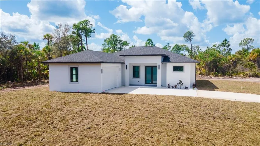 Back of property featuring a yard, an attached garage, and roof with shingles