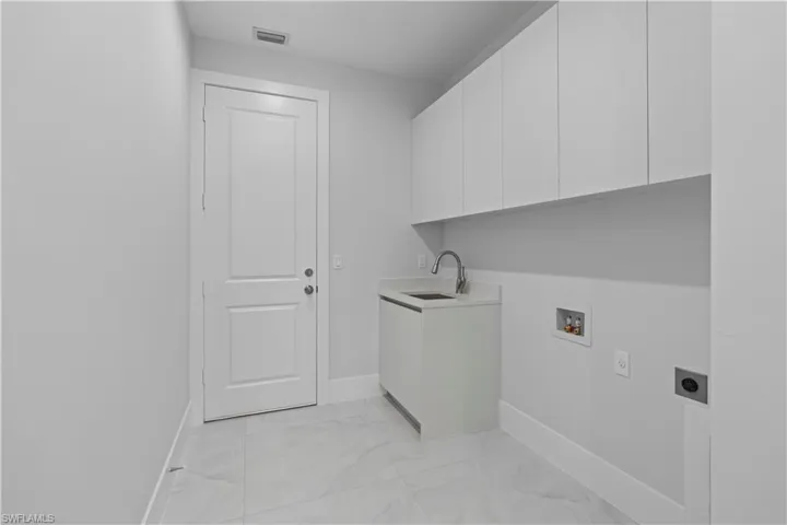 Laundry area featuring light marble finish flooring, electric dryer hookup, cabinet space, and hookup for a washing machine