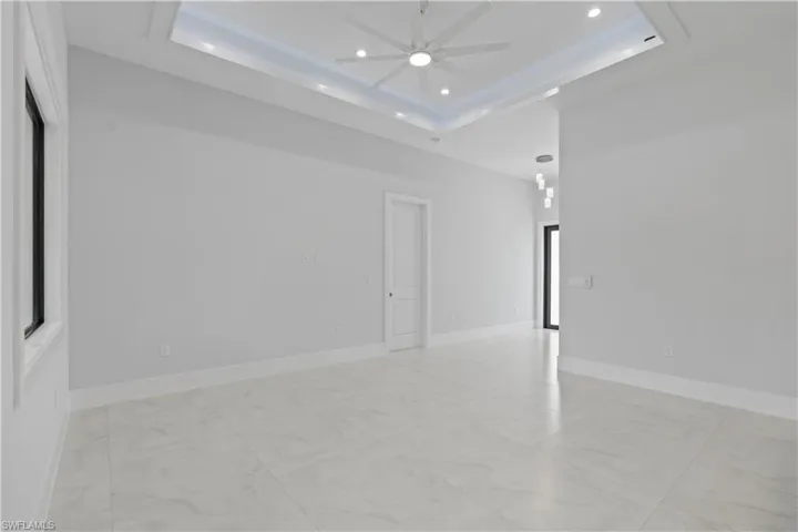 Spare room with a ceiling fan, recessed lighting, light marble finish flooring, and a raised ceiling
