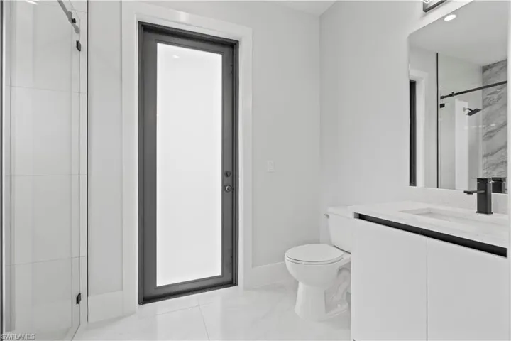 Bathroom featuring a stall shower, vanity, light marble finish floors, and recessed lighting