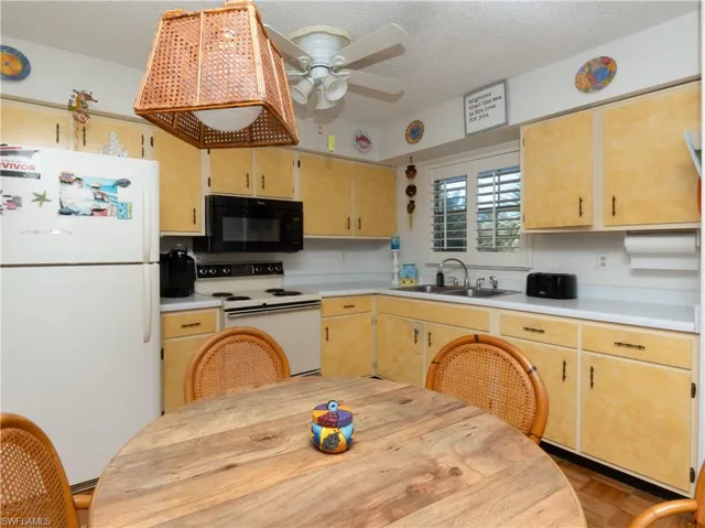 Kitchen with white appliances, light countertops, a textured ceiling, a ceiling fan, and light brown cabinets