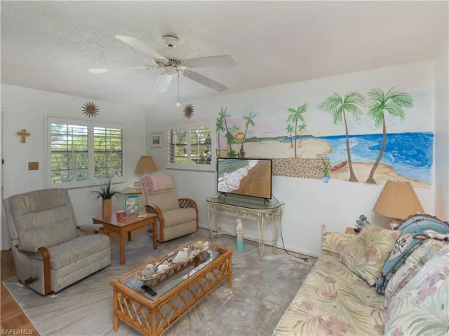 Living area with a ceiling fan and a textured ceiling
