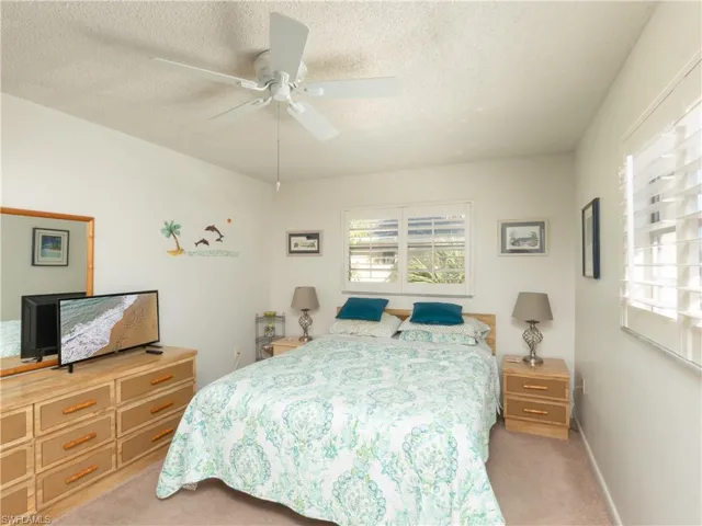 Bedroom with light carpet, ceiling fan, and a textured ceiling