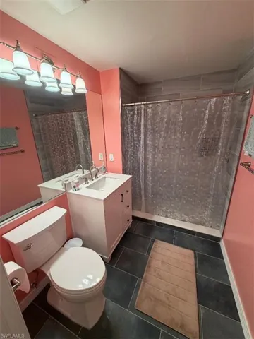 Bathroom featuring a tile shower, dark tile patterned flooring, and vanity