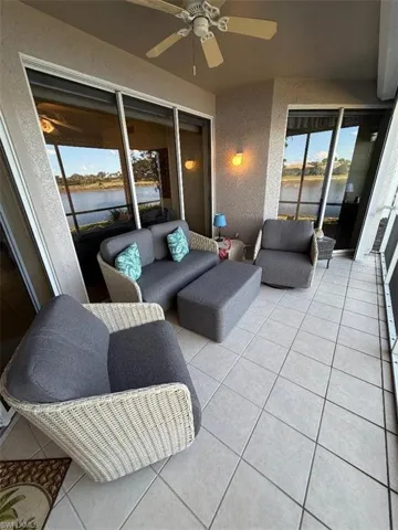 Sunroom / solarium with a textured wall, a water view, tile patterned flooring, and plenty of natural light