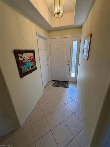 Foyer featuring light tile patterned flooring, a tray ceiling, and a chandelier