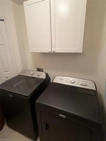 Laundry area featuring cabinet space, washer and dryer, and light tile patterned flooring