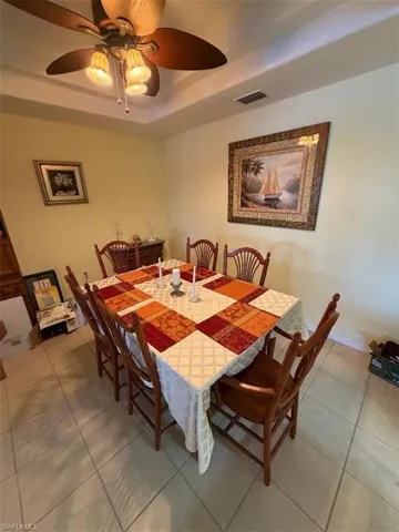 Tiled dining area with a raised ceiling and a ceiling fan