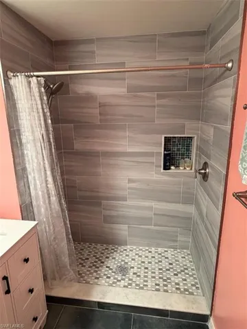 Bathroom featuring a stall shower, vanity, and dark tile patterned floors