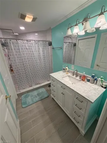 Bathroom featuring a stall shower, vanity, and wood finish floors