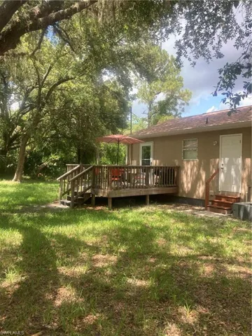 Back of house with a deck and a lawn