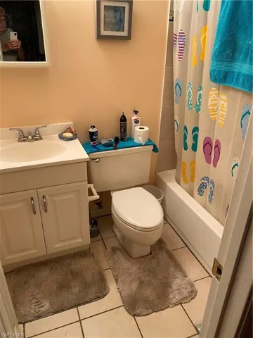 Full bathroom featuring shower / bath combo with shower curtain, tile patterned floors, toilet, and vanity