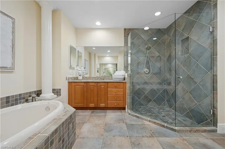 Primary en-suite bathroom with a bathtub, double vanities, tile shower, recessed lighting, and a toilet closet