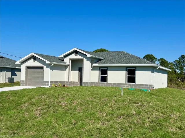 Ranch-style home featuring a garage, central AC, and a front yard
