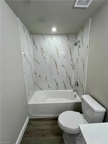 Full bathroom with tiled shower / bath, wood-type flooring, vanity, and toilet