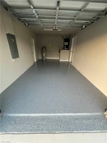 Garage featuring electric panel, electric water heater, and heating unit