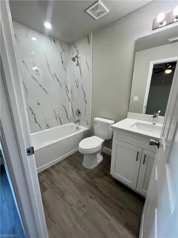 Full bathroom featuring tiled shower / bath, wood-type flooring, toilet, and vanity