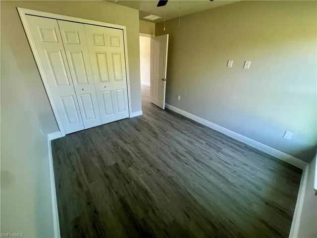Unfurnished bedroom with ceiling fan, dark hardwood / wood-style floors, and a closet