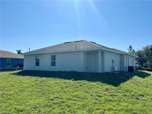 Back of house featuring central AC unit and a lawn