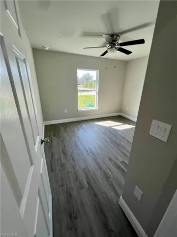 Spare room featuring dark wood-type flooring and ceiling fan