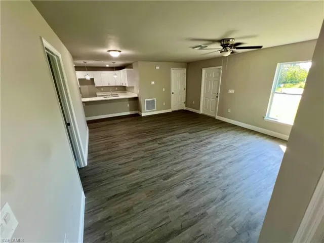 Unfurnished living room with sink, dark hardwood / wood-style floors, and ceiling fan