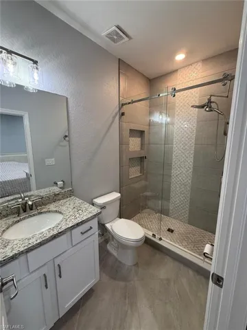 Bathroom featuring a textured wall, a shower stall, and vanity