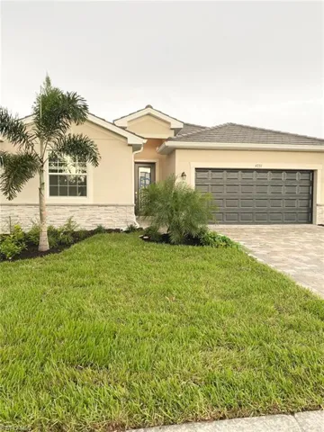 Ranch-style home featuring stone siding, a front yard, stucco siding, driveway, and an attached garage