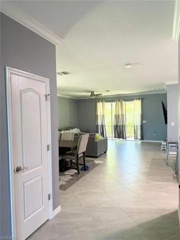 Hallway with ornamental molding and light tile patterned floors