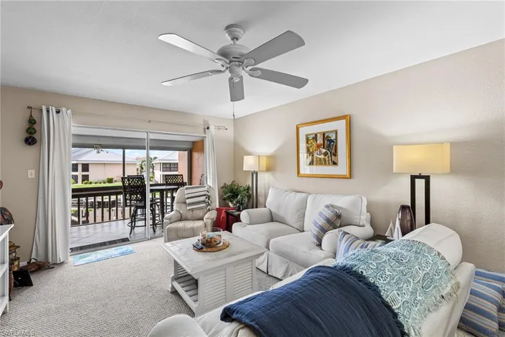 Carpeted living room featuring ceiling fan and a sunroom