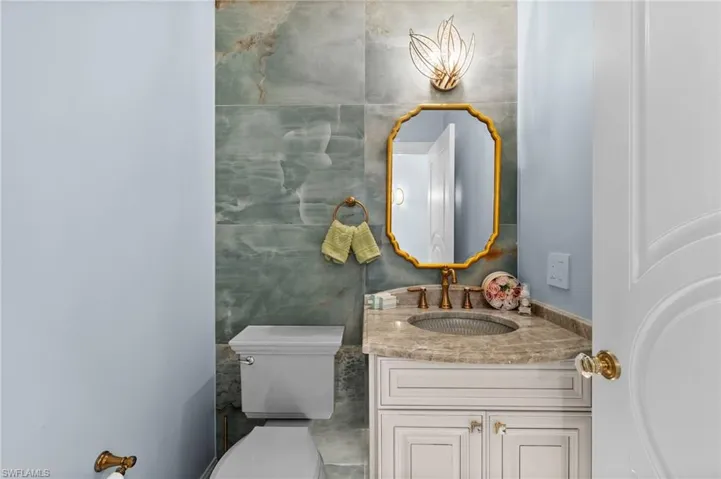 Powder Bathroom featuring tile walls, vanity, and upgraded toilet