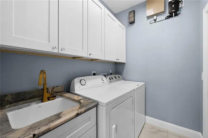 Laundry area featuring cabinets, sink, washing machine and clothes dryer
