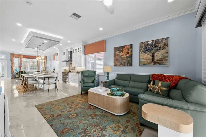 Living room with ceiling fan with notable chandelier and crown molding