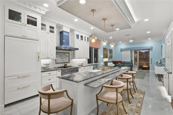 Kitchen featuring pendant lighting, a kitchen breakfast bar, a kitchen island, and white cabinetry