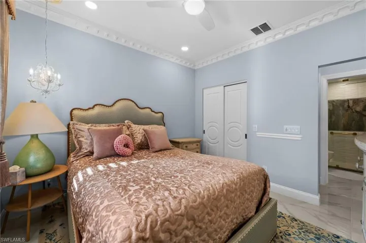 Bedroom with ceiling fan with notable chandelier, crown molding, and a closet