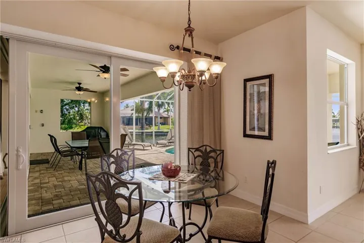 Tiled dining space with ceiling fan with notable chandelier