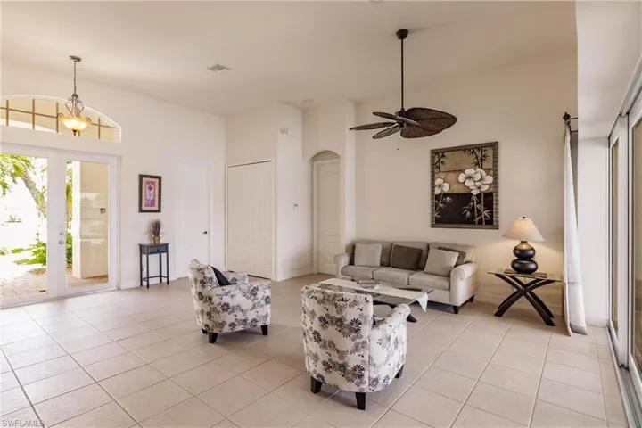 Tiled living room with ceiling fan with notable chandelier