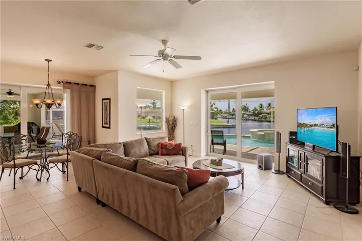 Tiled living room with ceiling fan with notable chandelier and a textured ceiling