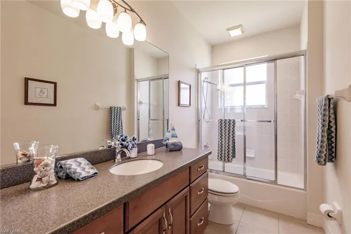 Full bathroom with toilet, bath / shower combo with glass door, tile patterned floors, and vanity
