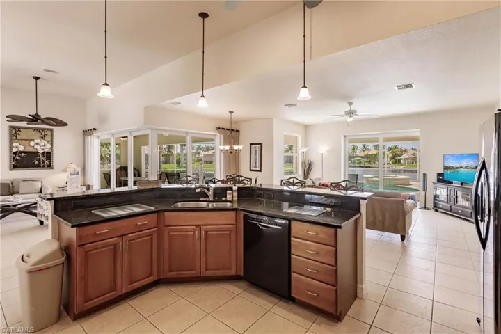 Kitchen with dishwasher, pendant lighting, sink, stainless steel fridge, and ceiling fan with notable chandelier