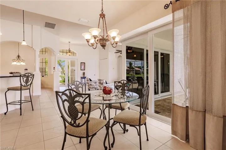 Dining area featuring light tile patterned flooring, an inviting chandelier, and ornate columns