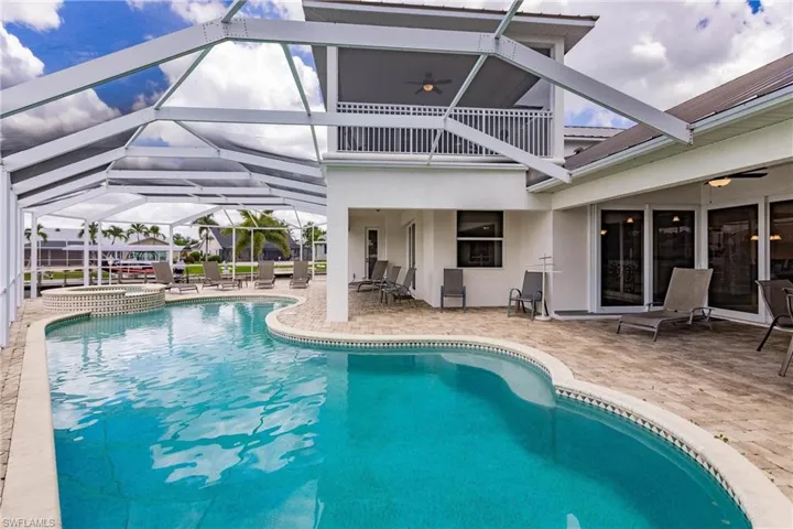 View of swimming pool featuring ceiling fan, glass enclosure, an in ground hot tub, and a patio