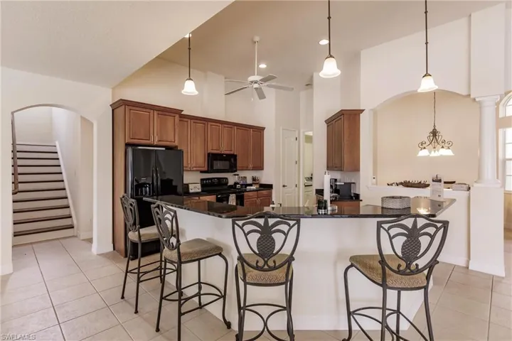 Kitchen featuring black appliances, light tile patterned floors, decorative light fixtures, and ceiling fan with notable chandelier