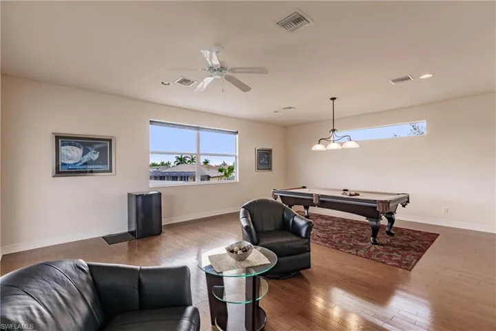 Rec room with ceiling fan, plenty of natural light, pool table, and hardwood / wood-style flooring