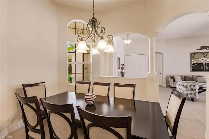 Dining room featuring a notable chandelier, light tile patterned floors, and decorative columns