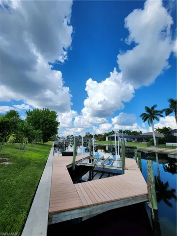 View of dock with a lawn and a water view